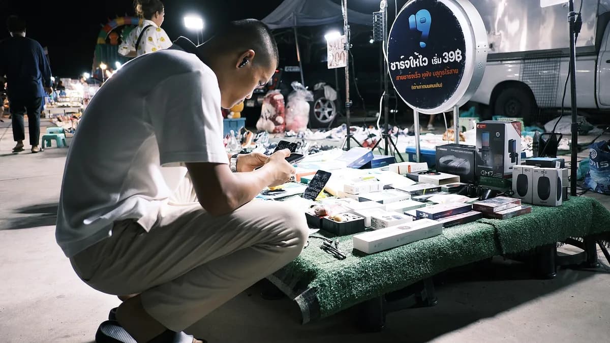 Prodavač pregleda mobitel na štandu s elektronikom i opremom