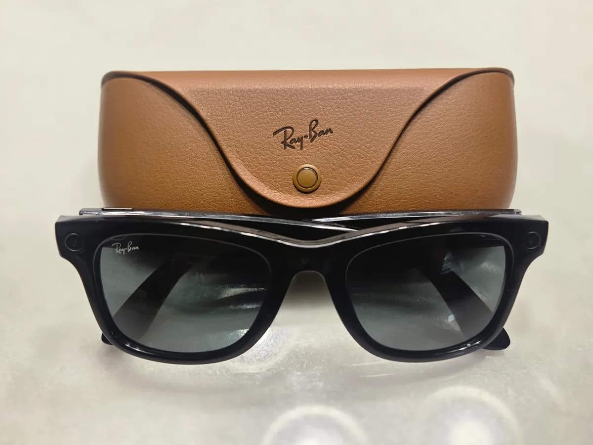 Ilustracija: pametne naočale Ray-Ban Meta prve generacije ispred kožne futrole za punjenje.