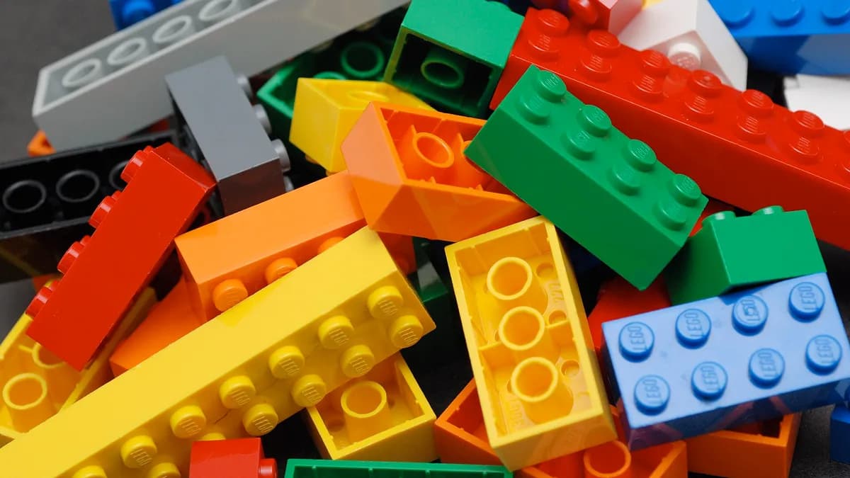 Ilustracija: gomila LEGO kockica raznih boja i veličina.