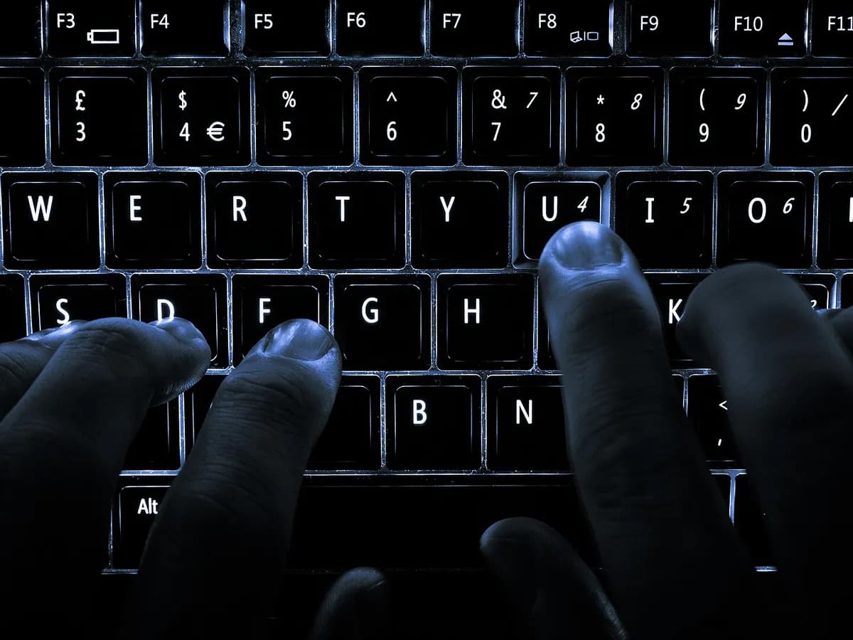 Prsti na osvijetljenoj tastaturi laptopa