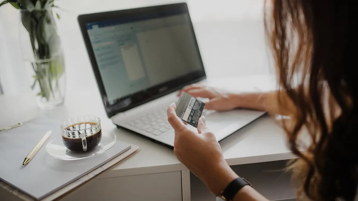 Žena drži platnu karticu dok kupuje preko laptopa