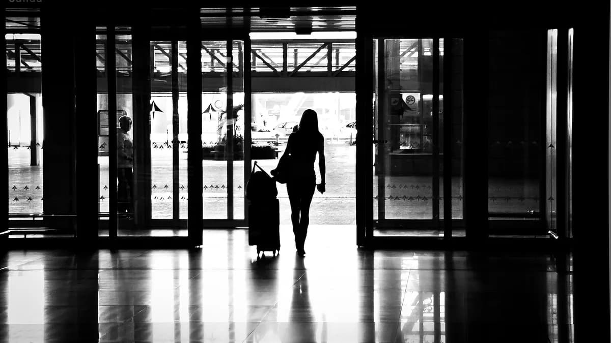 Putnica s koferom izlazi iz zgrade aerodroma