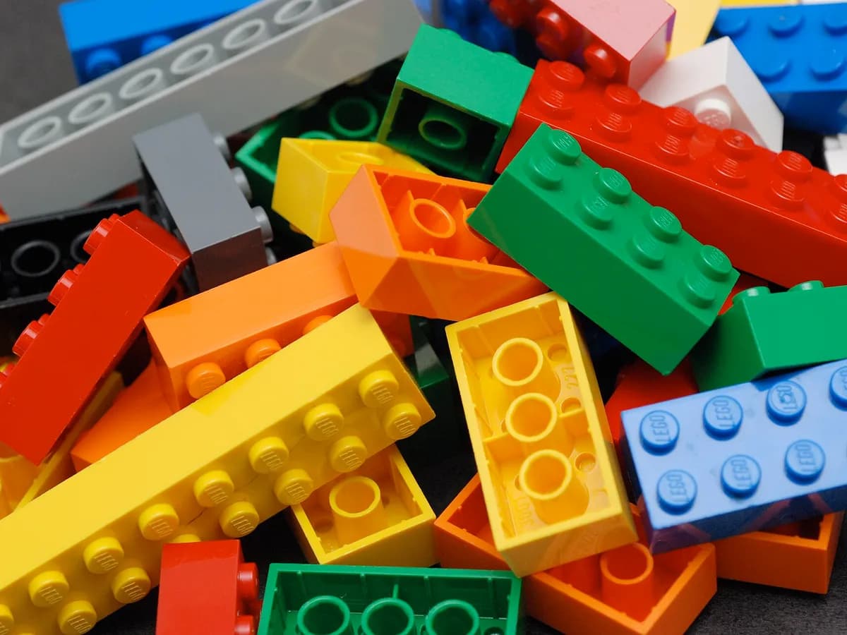 Ilustracija: gomila LEGO kockica raznih boja i veličina.