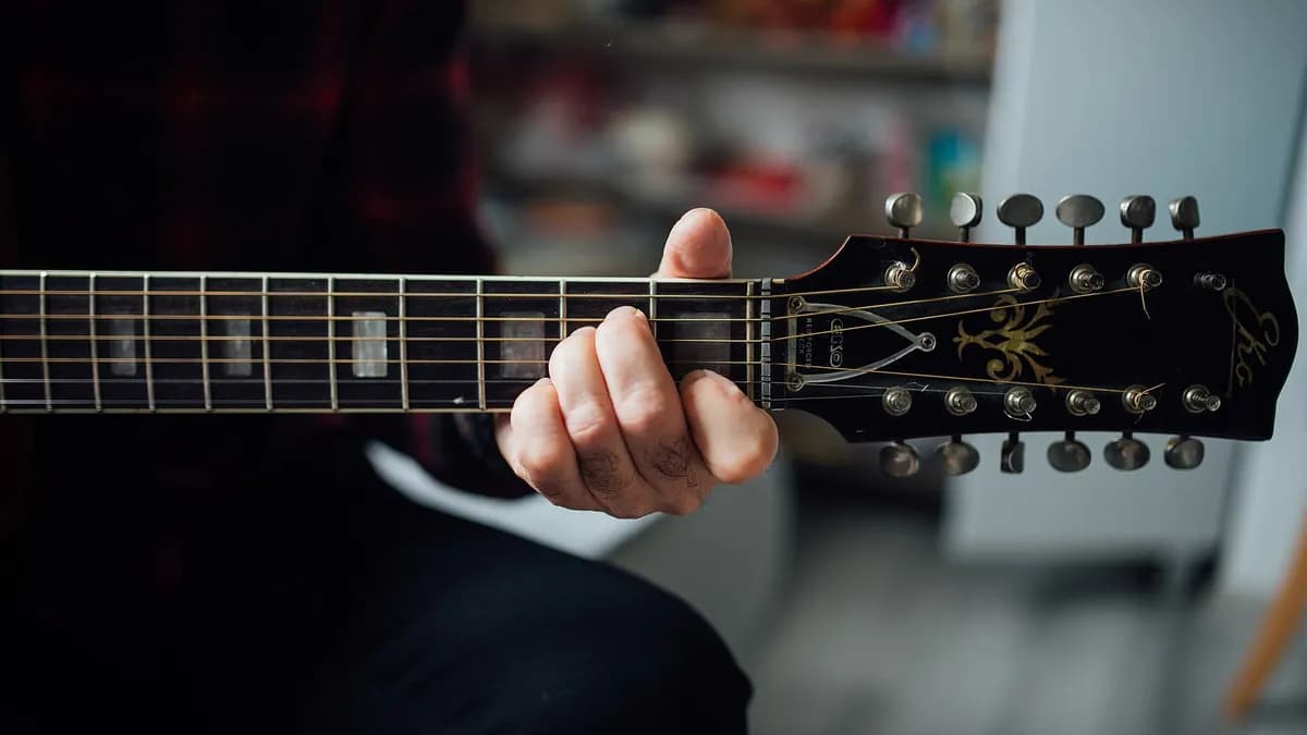 Šaka hvata A-mol akord na vratu akustične gitare